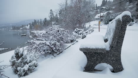 Snow-falling-on-stone-bench-by-the-lake