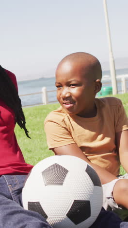 video de un feliz padre y hijo afroamericanos divirtiéndose con la pelota al aire libre