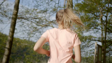 Woman-running-in-woods-while-hair-sways-on-sunny-day