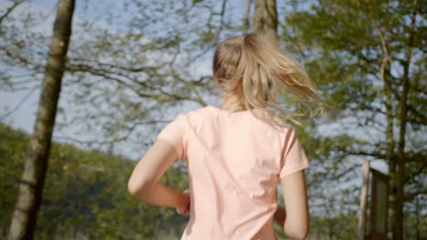 mujer corriendo en el bosque mientras el cabello se balancea en un día soleado