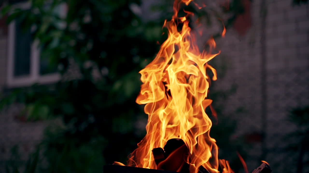 Slow motion of burning logs in campfire. Combustion of wood in vivid flame in the evening. Bright fire motion outdoors.