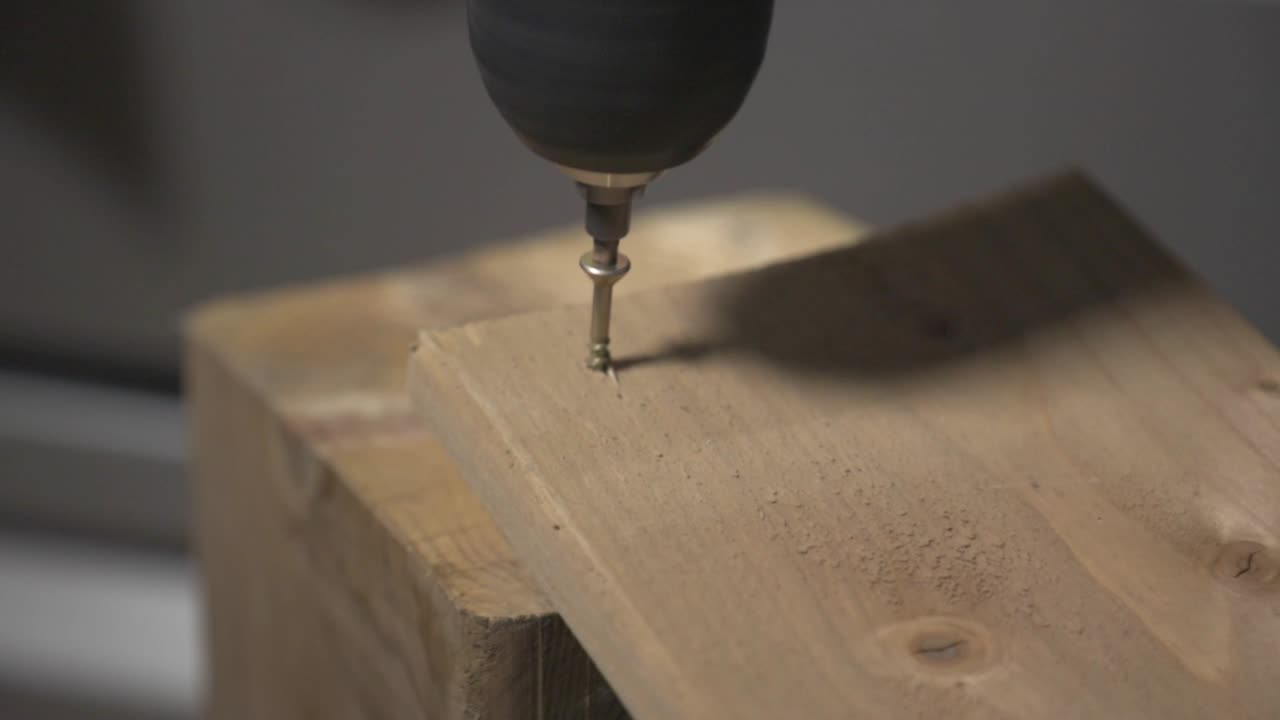 An Electric Screwdriver Drilling Wood With A Screw. - close up shot