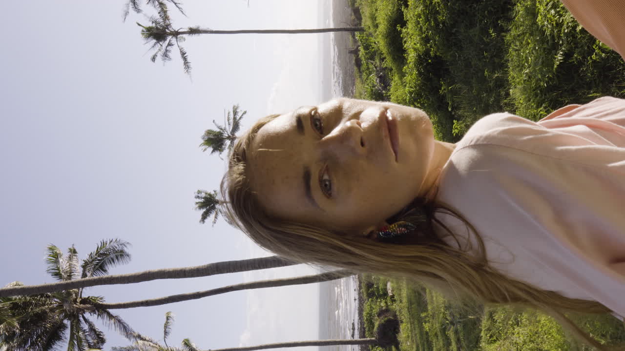Close up gimbal shot of blonde woman looking at camera in beach landscape