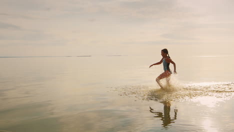 Despreocupada-Niña-De-7-Años-Corriendo-En-El-Agua-De-Sus-Pies-Volando-Muchas-Salpicaduras-En-Cámara-Lenta