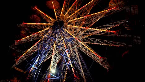 carnival ferris wheel with lights at night. families with kids celebrate summer.