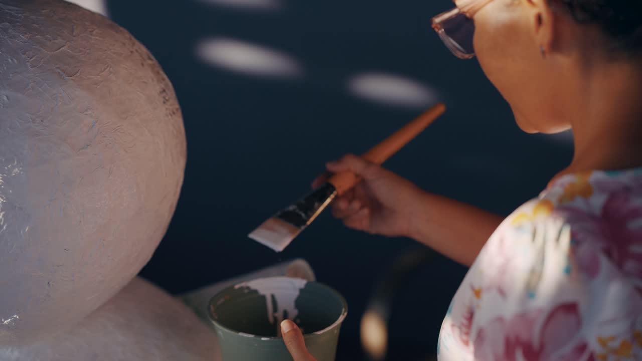 A woman painting a large object with a paintbrush
