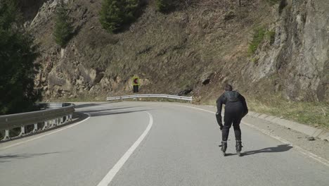 a skilled skater in black gear speeds downhill on a winding mountain road, embracing the thrill of extreme inline skating. ideal for action sports, adventure, and fitness content.