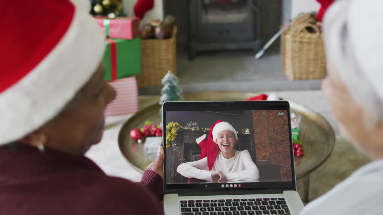 diversas amigas mayores que usan una computadora portátil para una videollamada de navidad con una mujer feliz en la pantalla