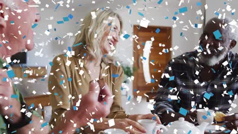 confetti falling against group of senior people smiling while having coffee together at home