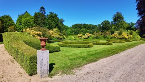 manicured topiary and garden sculptures along a wide sunny pathway at upper brittany botanical park, le chatellier, france.