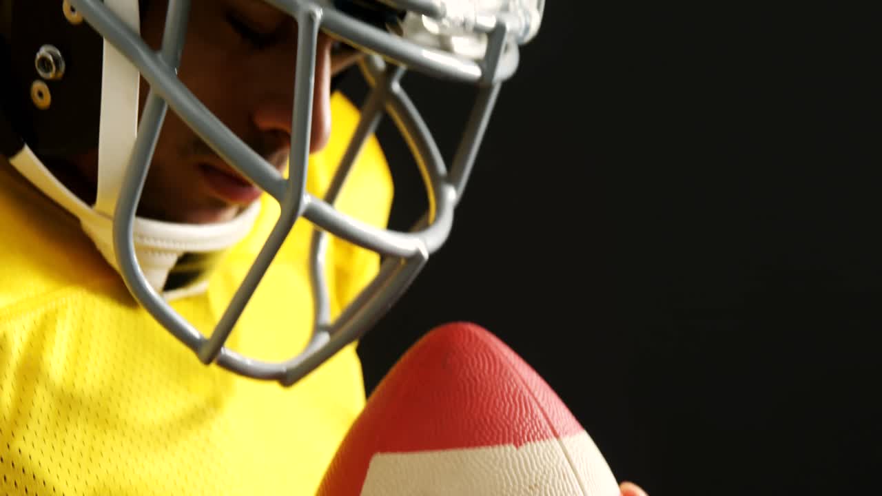 Giocatore di football americano con il pallone in mano su sfondo nero 4k