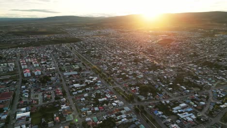 Sun-Rises-in-Punta-Arena-Chile-above-Andean-Cordillera-Mountain-Range-Aerial-Top-View-of-the-City,-Streets,-Houses,-Cityscape-in-Warm-Summer-Weather