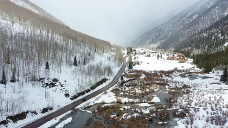 majestic forestry mountain slopes covered in snow during snowfall, aerial drone side fly view