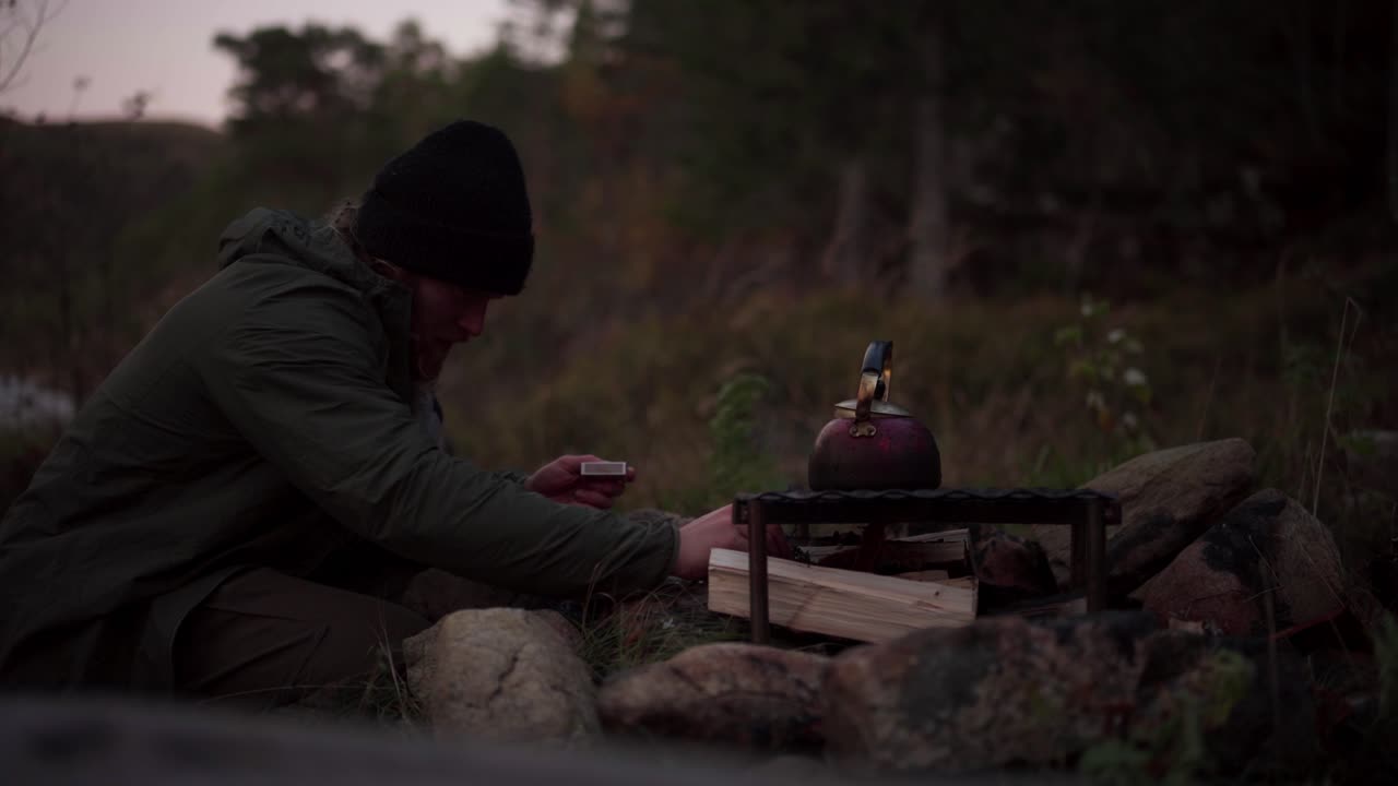 Hildremsvatnet, Trøndelag, Noorwegen - Een man gebruikt houtblokken om te koken - Close-up