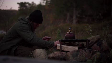hildremsvatnet, trondelag, norway - a man is utilizing wooden pieces for cooking - close up