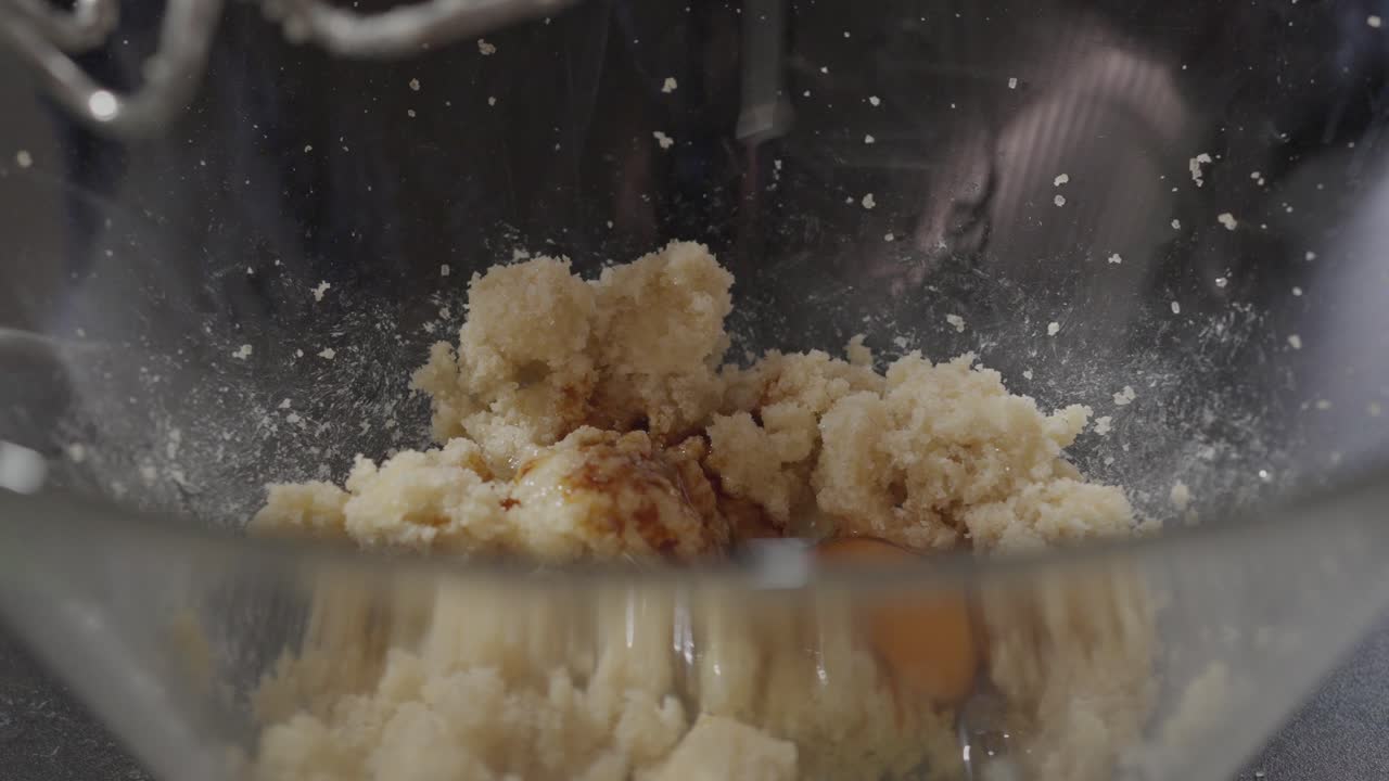Menambahkan Telur ke Adonan Kue Kering Sambil Mengocok dengan Mixer Tangan Tampak Dekat.