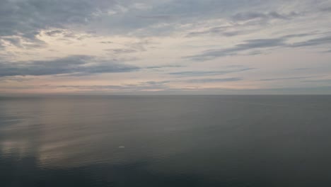 Surface-Of-A-Sea-Under-The-Cloudy-Sky-At-Sunset---drone-shot