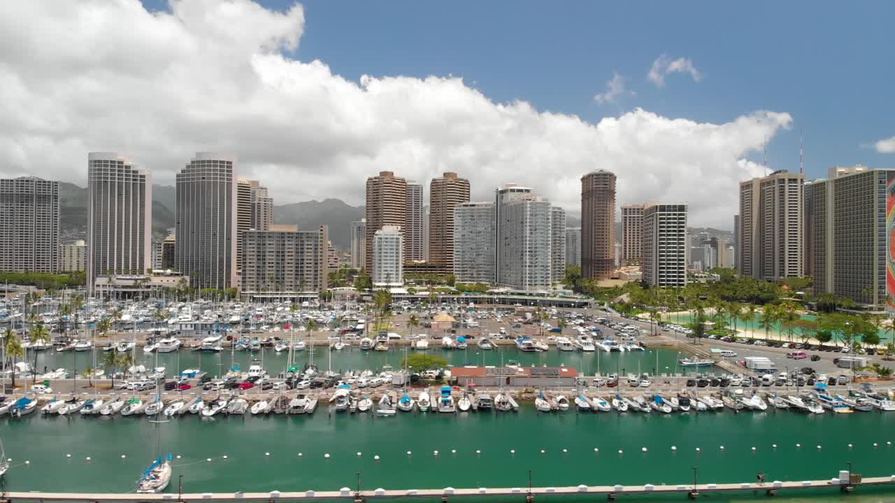Smooth Aerial Sideways Movement over Boat Harbor and Kahanamoku Lagoon with Honolulu skyscrapers in the background.