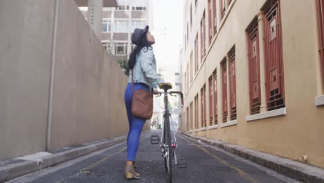 mixed race woman walking next to her bike on the street