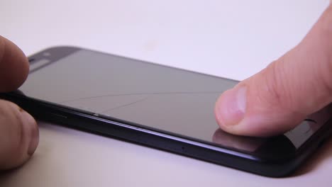 male inspecting mobile phone screen with broken safety glass