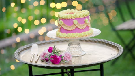 Rosafarbener-Herzkuchen-Mit-Gelbem-Zuckerguss-Auf-Silbernem-Serviertablett-Mit-Rosen,-4K-Zeitlupe