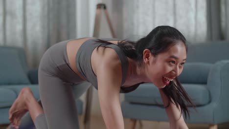 close up portrait of young asian athletic female in sports clothes doing cardio high knees and core strengthening exercises during workout on the mat at home