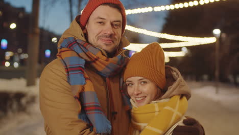 retrato de pareja feliz en la calle con luces de navidad