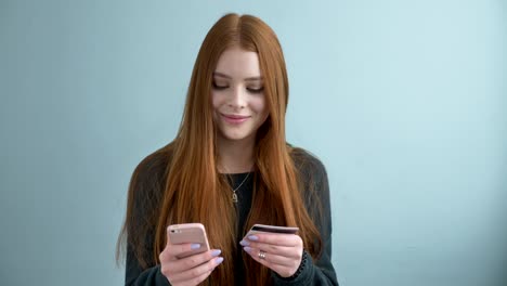 joven hermosa chica pelirroja hace una compra en línea, banca en línea usando teléfono inteligente compras en línea con tarjeta de crédito en el estilo de vida de casa. tecnología e internet concepto 60 fps