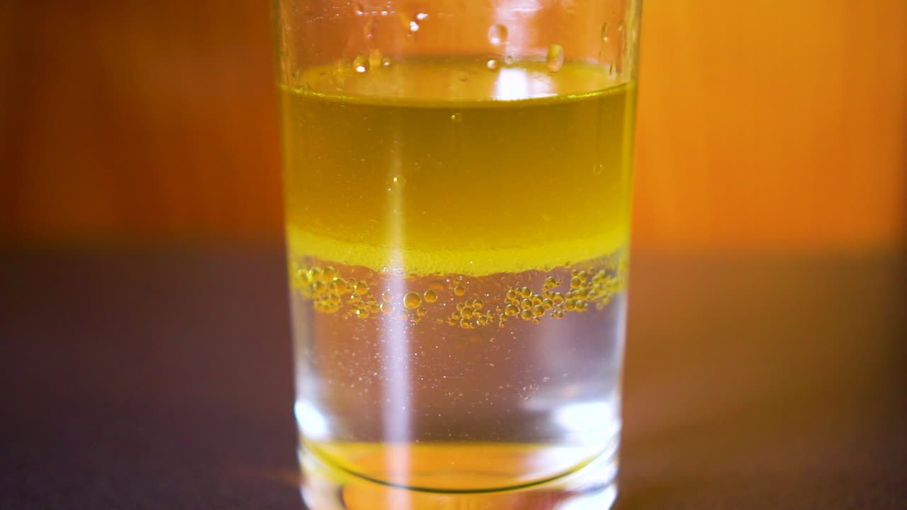 Time-lapse di acqua e olio che si separano in due strati in un bicchiere