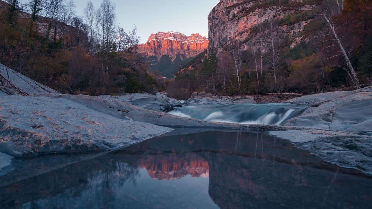 Small lake reflection in Ordesa National park Mondarruego mountain catching last sunrays during sunset timelapse in fall autumn season
