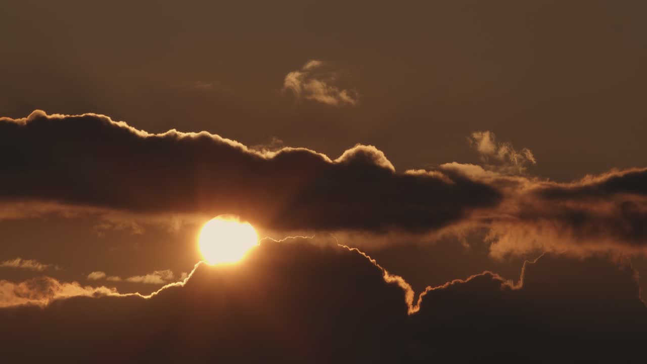 Solen går langsomt ned bag skyerne, solnedgang, statisk vidvinkelskud.