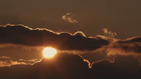el sol se pone lentamente detrás de las nubes, la puesta de sol, el tiro ancho estático