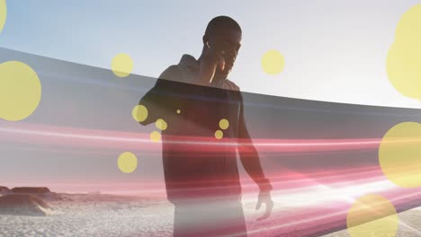 Animation-of-spots-over-african-american-man-with-earphones-at-beach