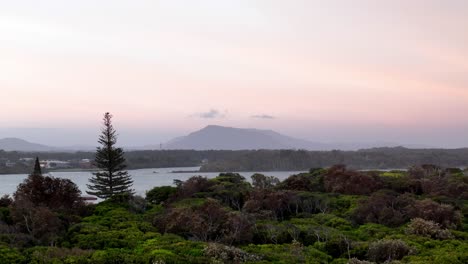 Dämmerungsruhe-über-Einer-Küstenlandschaft,-Bergsilhouette-Vor-Einem-Pastellfarbenen-Himmel