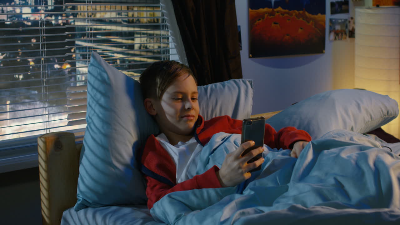 십대는 밤에 침대에서 스마트폰을 사용합니다.