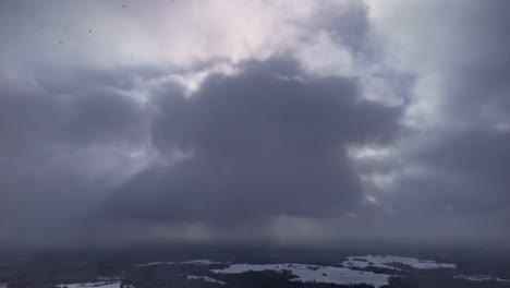 dark storm clouds gathering over sky, soft light breaking through moody atmosphere, aerial snowing static backdrop