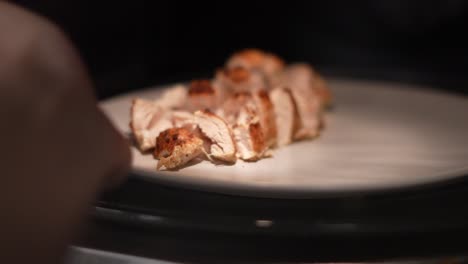 Close-up-of-reheating-plate-with-sliced-cooked-chicken-breast-in-microwave