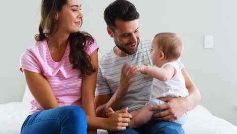 Parents-playing-with-their-baby-girl-in-bedroom