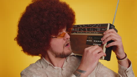 man with afro wig dancing with vintage radio