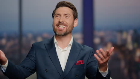 un invitado del programa sonriente hablando con un presentador desconocido en el canal de estudio de cerca.