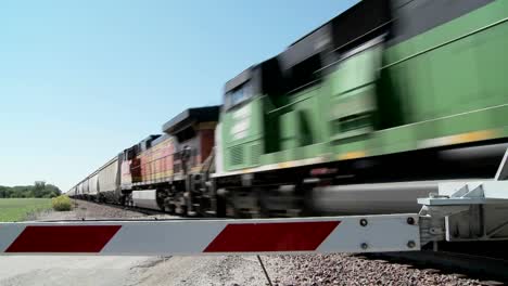 a freight train speeds past a gated railroad crossing