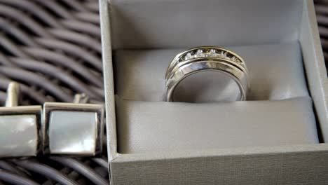 sliding shot of a groom’s silver wedding ring and cufflinks