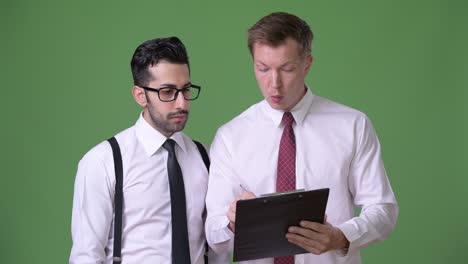 dos jóvenes empresarios multiétnicos trabajando juntos contra un fondo verde