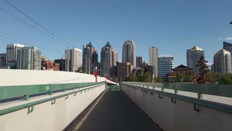 City-skyscrapers-approached-from-a-pedestrian-bridge-on-a-sunny-day-POV-Calgary-Alberta-Canada