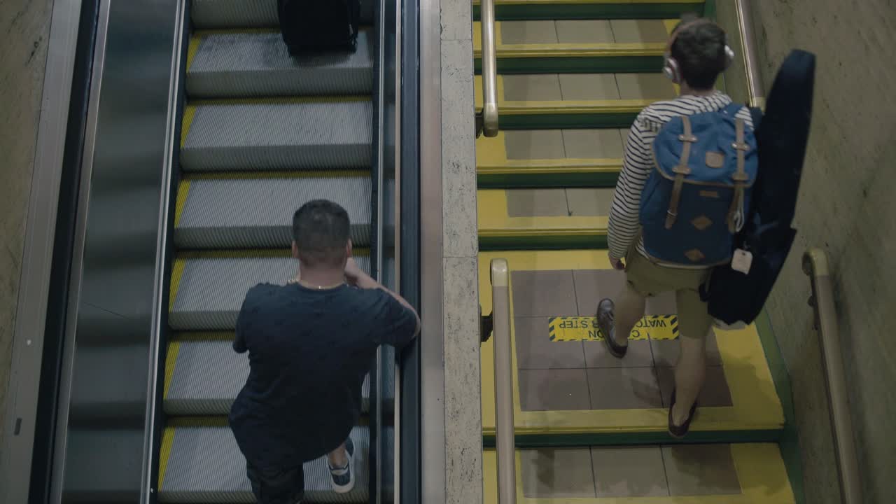 A group of people take an escalator up alongside others that are walking up stairs.