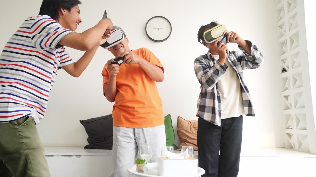 Young Asian Man Taking Pictures And Selfie Of His Family Playing Video Games Using Smartphone