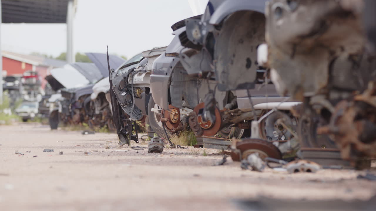 Shallow focus low angle slider of abandoned rusty vehicles at scrapyard
