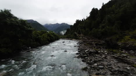 fpv cinematográfico filmado por encima de un pequeño río y bosque en la cordillera de nueva zelanda