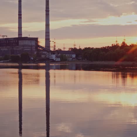 river at sunset on manufacturing background. industrial pipes reflect in the evening water. metallurgical plant near the river.
