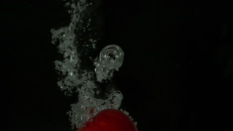 Red-apple-plunging-into-water-on-black-background